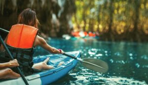 Women in canoe paddles down a creek.
